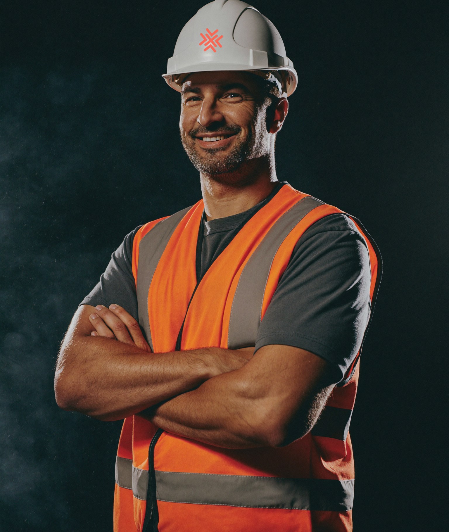 Portrait of a construction worker in a hard hat and high-visibility jacket, lit against a dark background